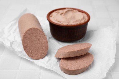 Photo of Delicious liver sausage and paste on white tiled table