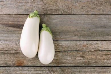 Photo of Fresh white eggplants on wooden table, flat lay. Space for text