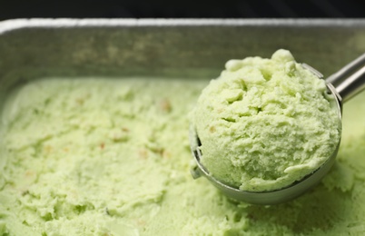 Photo of Container and scoop of sweet pistachio ice cream, closeup
