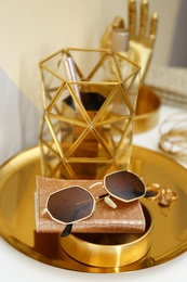 Photo of Gold tray with notebook, glasses and accessories on dressing table