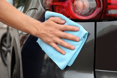 Man washing car headlight with rag, closeup