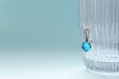 Beautiful necklace with gemstone on light blue background, space for text. Luxury jewelry