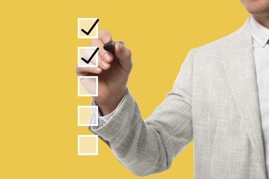 To Do List. Man ticking check boxes with marker on glass board against yellow background, closeup