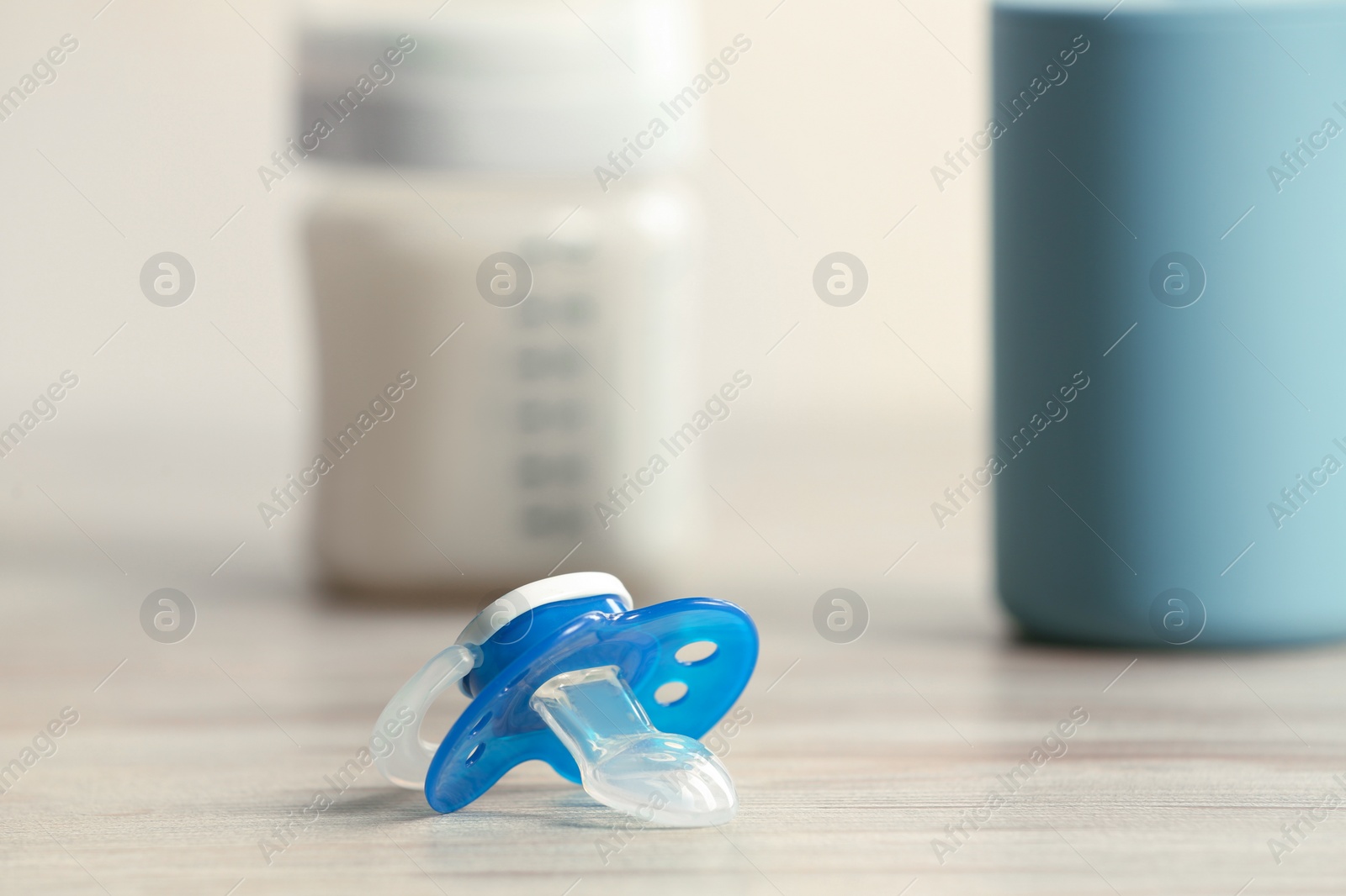 Photo of Baby pacifiers on beige table against blurred background, space for text