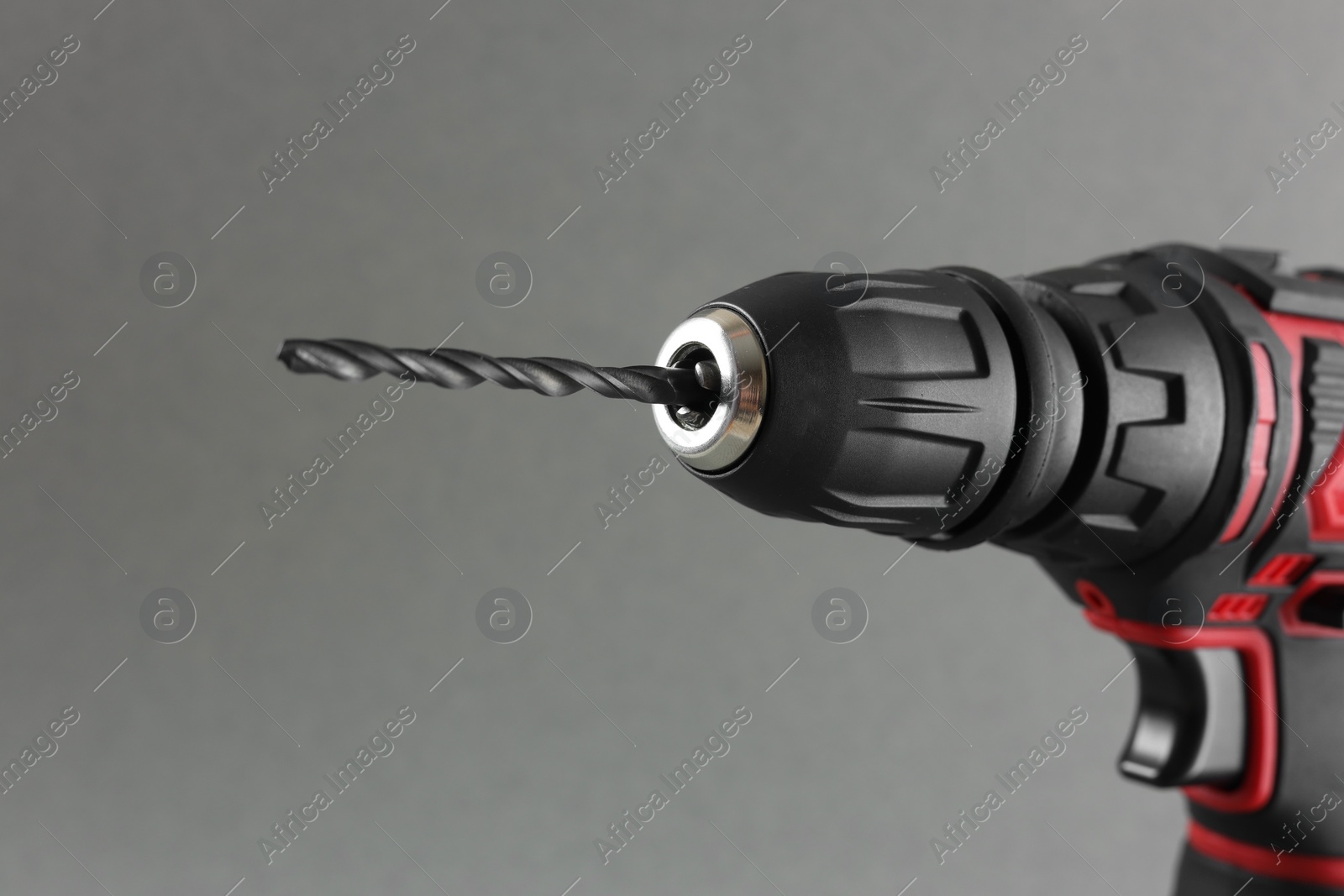 Photo of Modern electric screwdriver on grey background, closeup