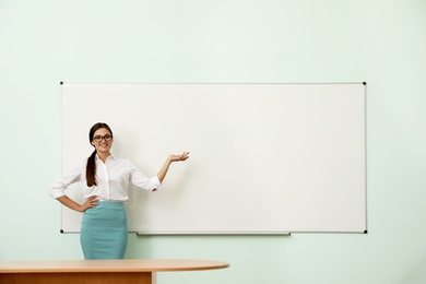 Photo of Female teacher near whiteboard in modern classroom