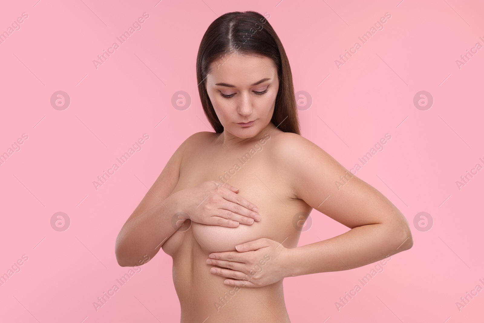 Photo of Mammology. Naked woman doing breast self-examination on pink background