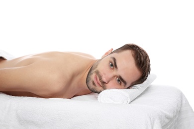 Photo of Handsome man relaxing on massage table against white background. Spa service