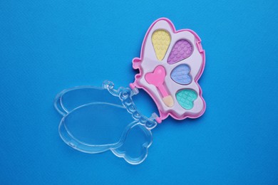 Photo of Decorative cosmetics for kids. Eye shadow palette on blue background, top view