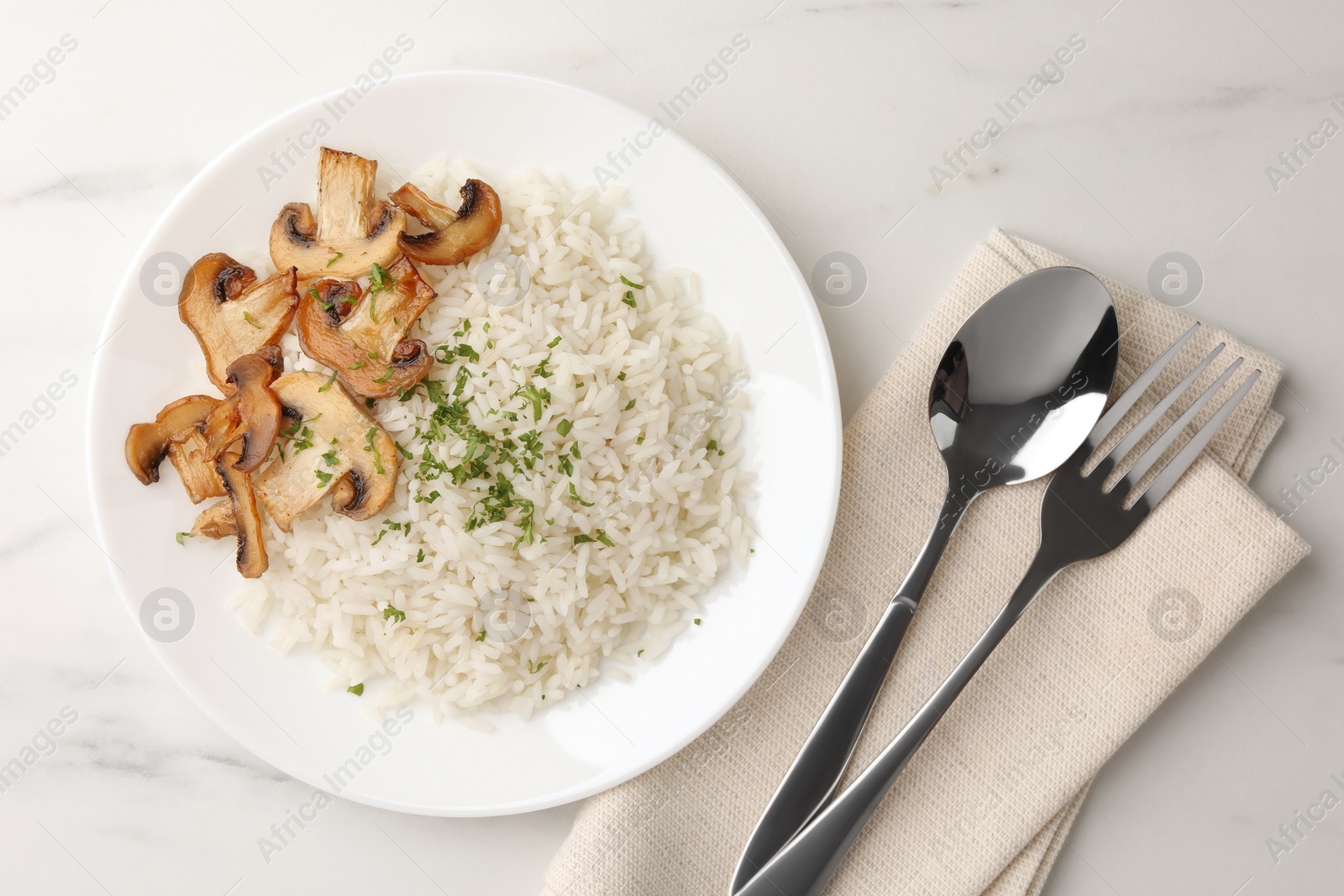 Photo of Delicious rice with parsley and mushrooms served on white marble table, flat lay