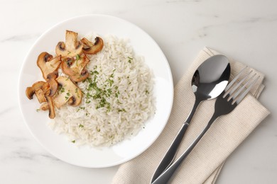 Delicious rice with parsley and mushrooms served on white marble table, flat lay