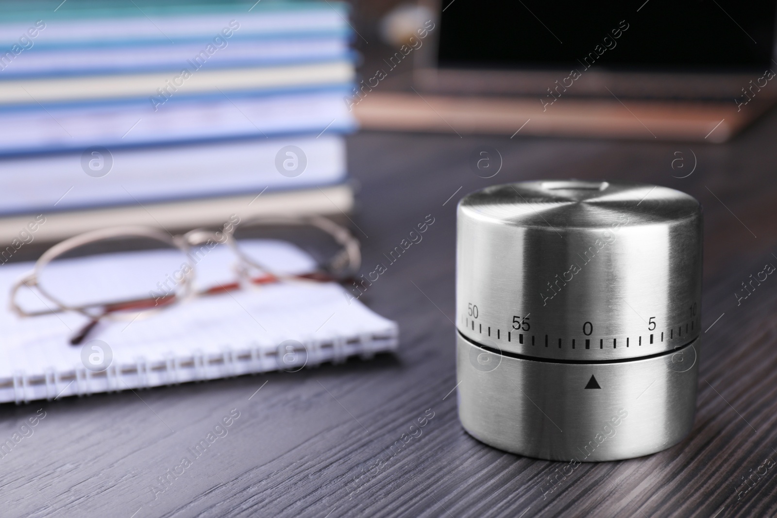 Photo of Kitchen timer, notebook and eyeglasses on wooden table, closeup. Space for text