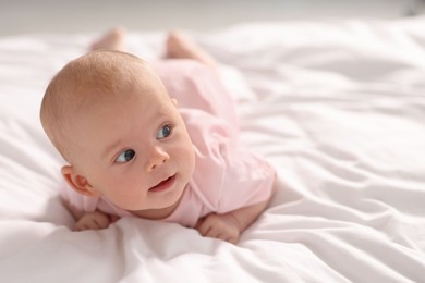 Photo of Cute little baby lying on white sheets, space for text