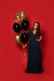 Photo of Happy woman with air balloons on red background. Christmas party