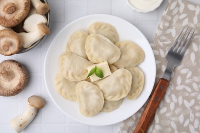 Delicious dumplings (varenyky) with mushrooms and butter served on white tiled table, flat lay
