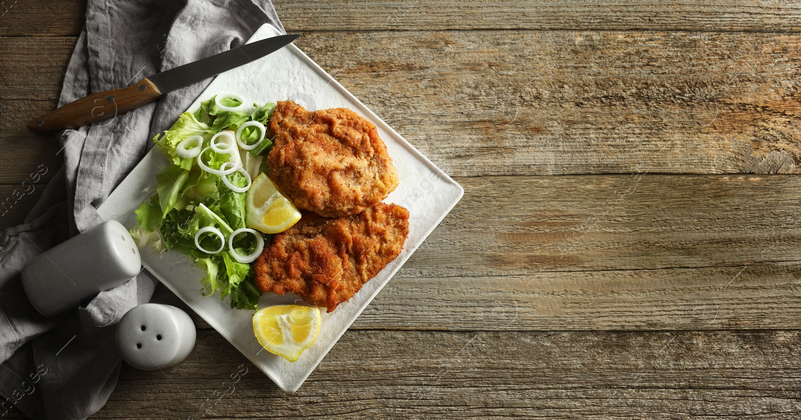 Image of Tasty schnitzels served on wooden table, flat lay. Banner design with space for text