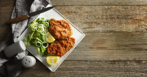 Image of Tasty schnitzels served on wooden table, flat lay. Banner design with space for text