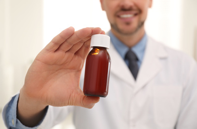 Professional pharmacist with syrup in drugstore, closeup