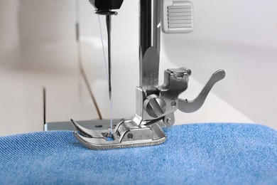 Photo of Sewing machine with light blue cloth, closeup