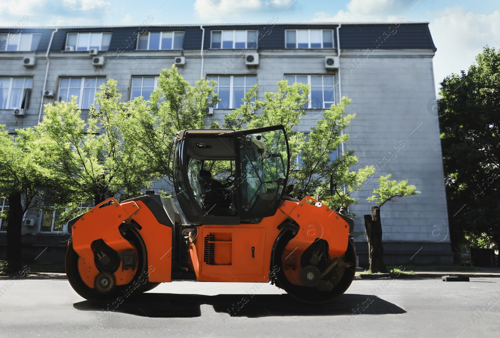 Image of Roller working on city street. Road repairing