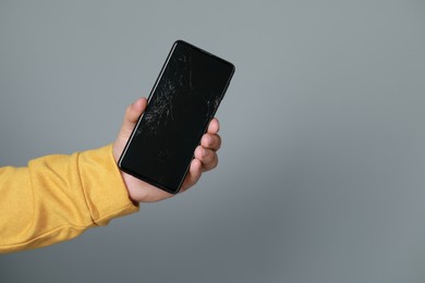 Photo of Man holding damaged smartphone on light grey background, closeup with space for text. Device repairing