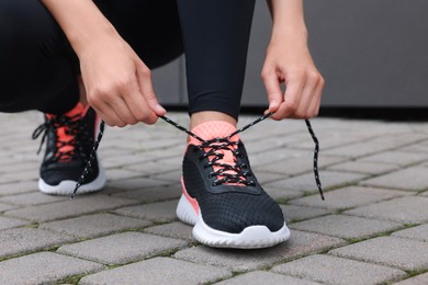 Photo of Woman tying shoelacesneakers on street, closeup