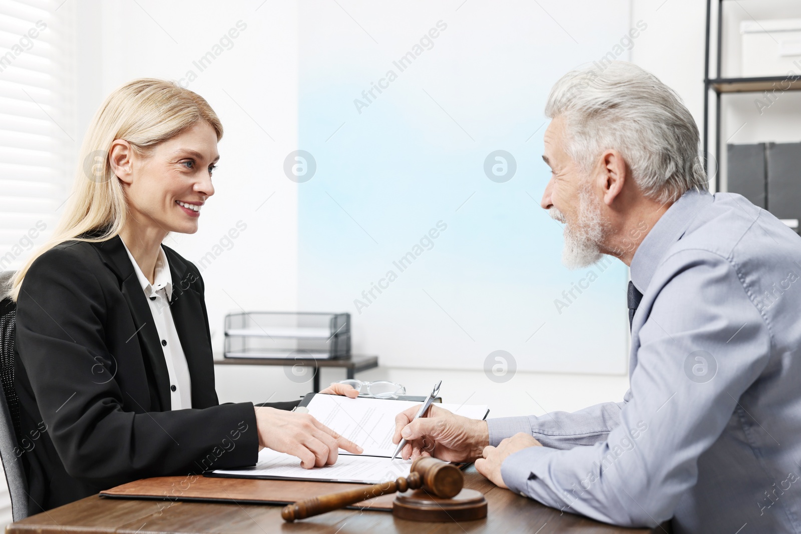 Photo of Senior man signing document in lawyer's office