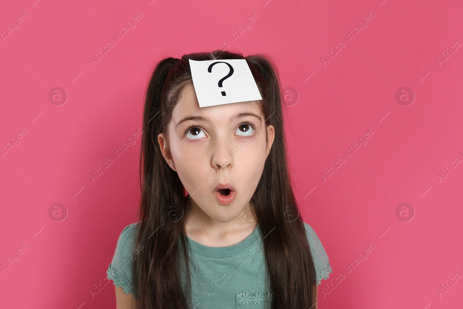 Photo of Emotional girl with question mark sticker on forehead against pink background