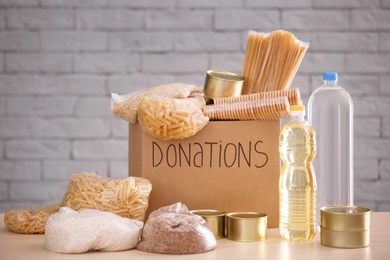 Donation box with food on table against brick wall