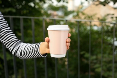 Photo of Coffee to go. Woman with paper cup of drink outdoors, closeup. Space for text
