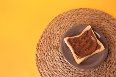 Photo of Tasty toast with chocolate paste and flax seeds on yellow background, above view. Space for text