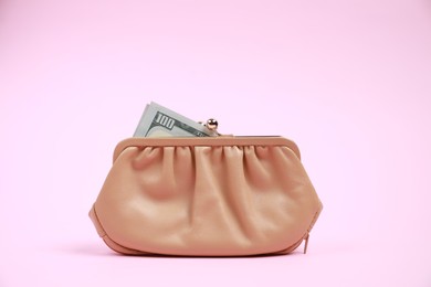 Photo of Stylish beige leather purse with dollar banknote on pink background