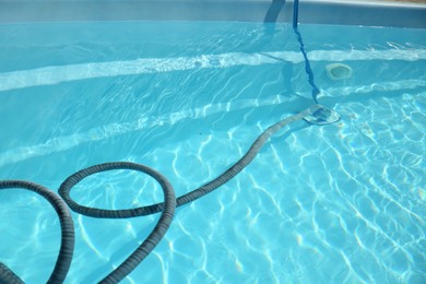 Photo of Cleaning outdoor swimming pool with underwater vacuum