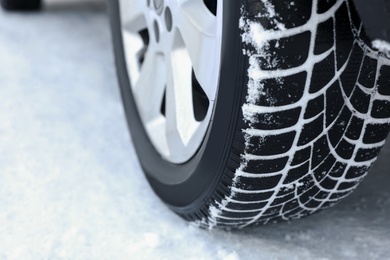 Car with winter tires on snowy road, closeup view