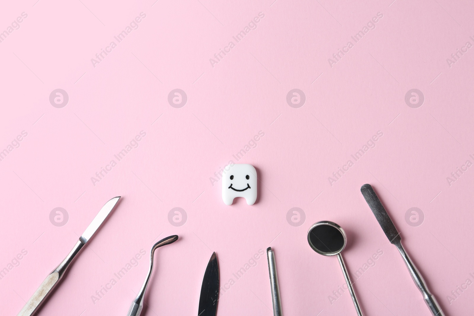 Photo of Professional dental tools and small plastic tooth on color background, flat lay