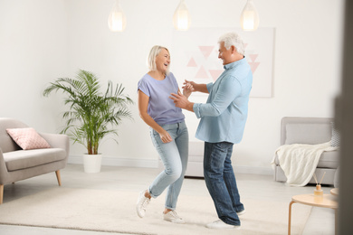 Photo of Happy mature couple dancing together in living room