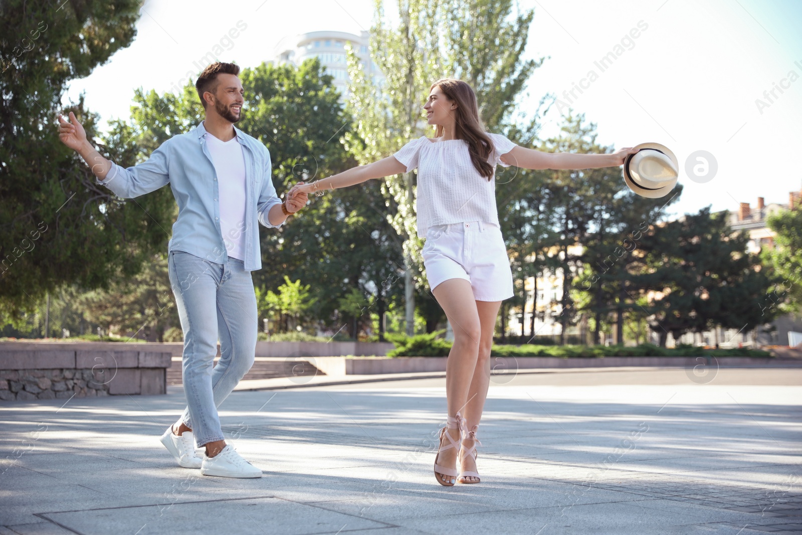 Photo of Lovely young couple dancing together outdoors on sunny day