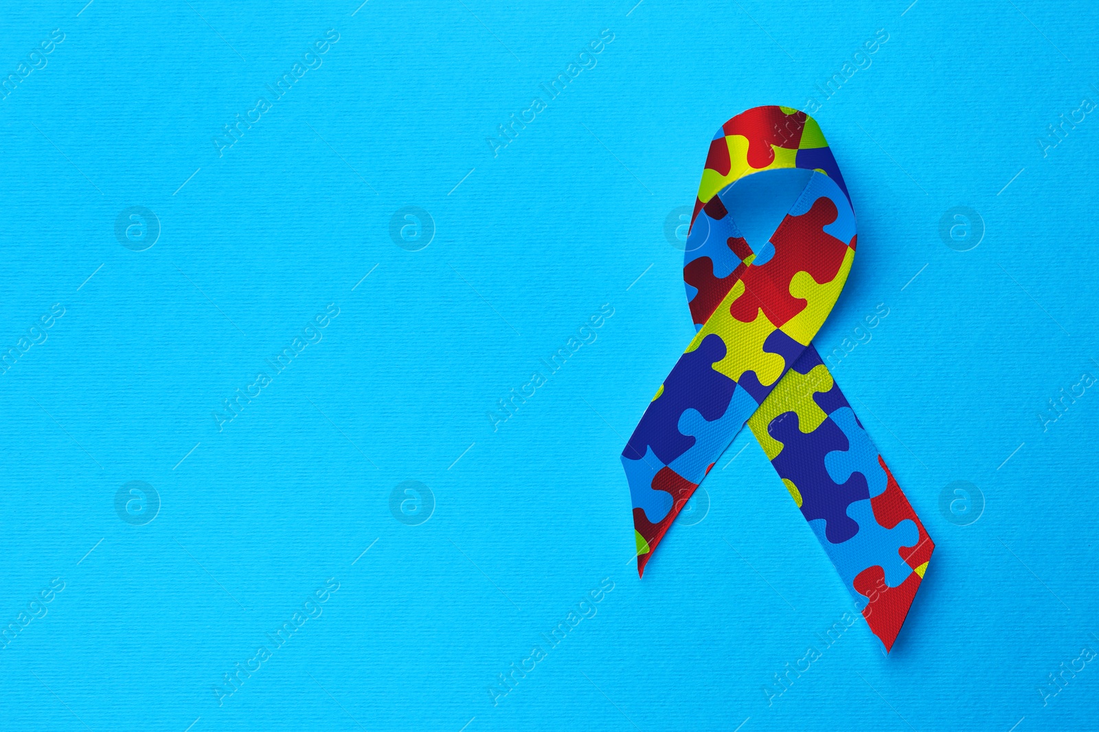 Image of World Autism Awareness Day. Colorful puzzle ribbon on turquoise background, top view with space for text