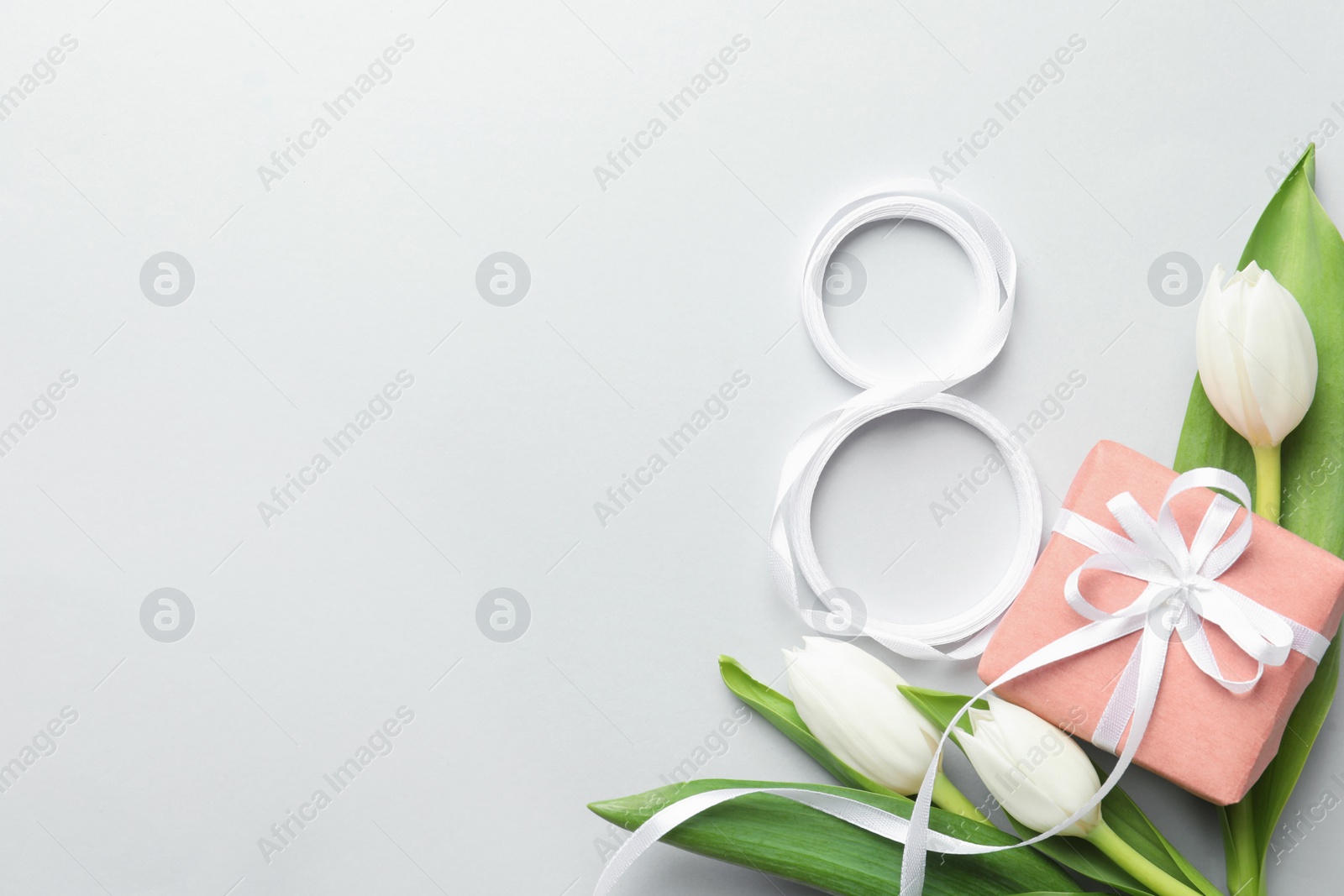 Photo of 8 March card design with tulips, gift and space for text on light grey background, flat lay. International Women's Day