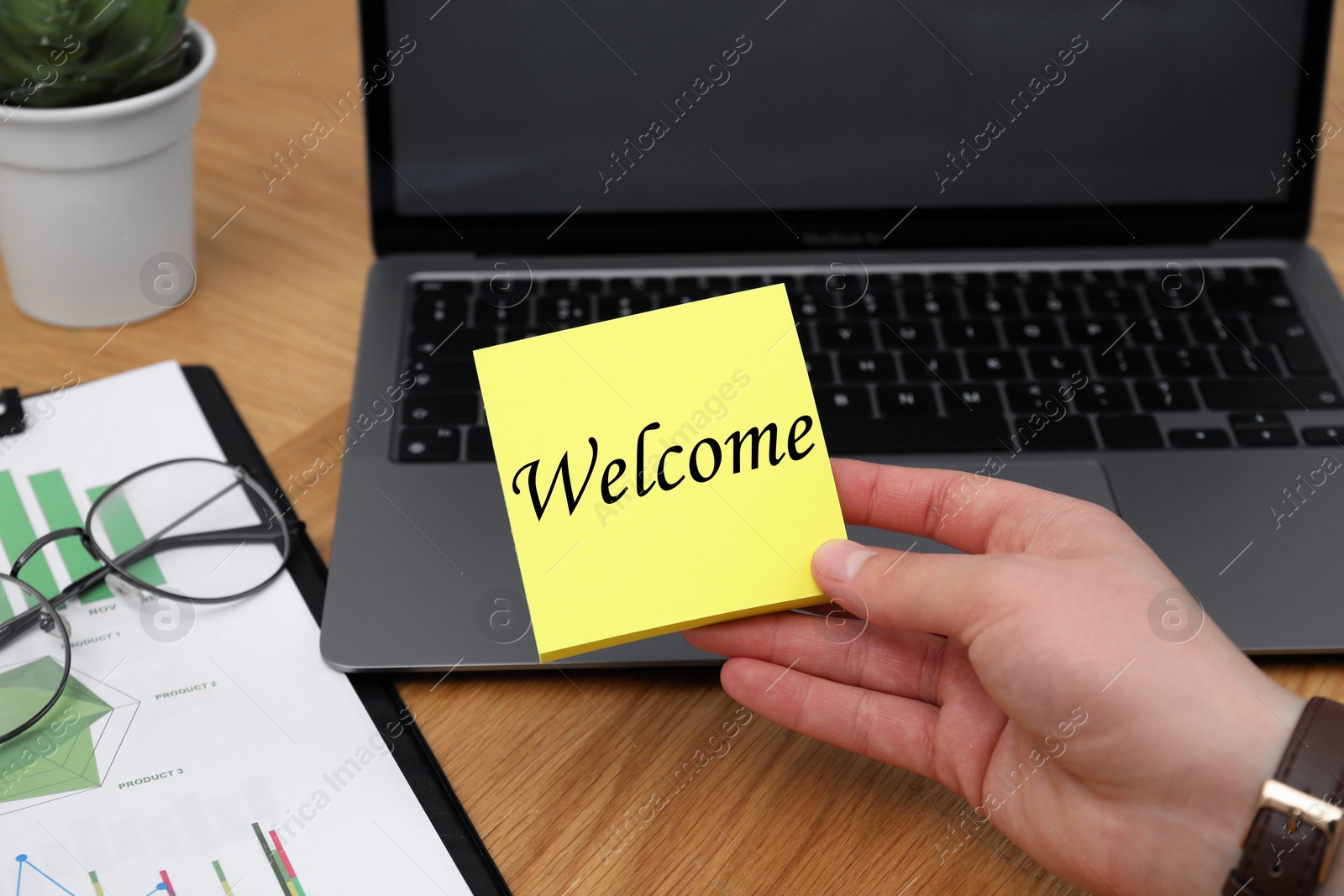 Image of Man holding paper note with word Welcome at his office desk, closeup