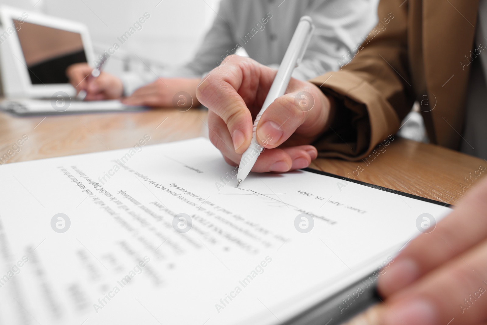 Photo of Woman signing contract at table in office, closeup.