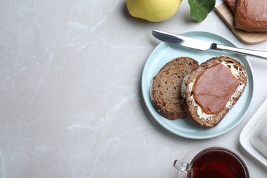 Photo of Tasty sandwich with quince paste served for breakfast on light grey marble table, flat lay. Space for text