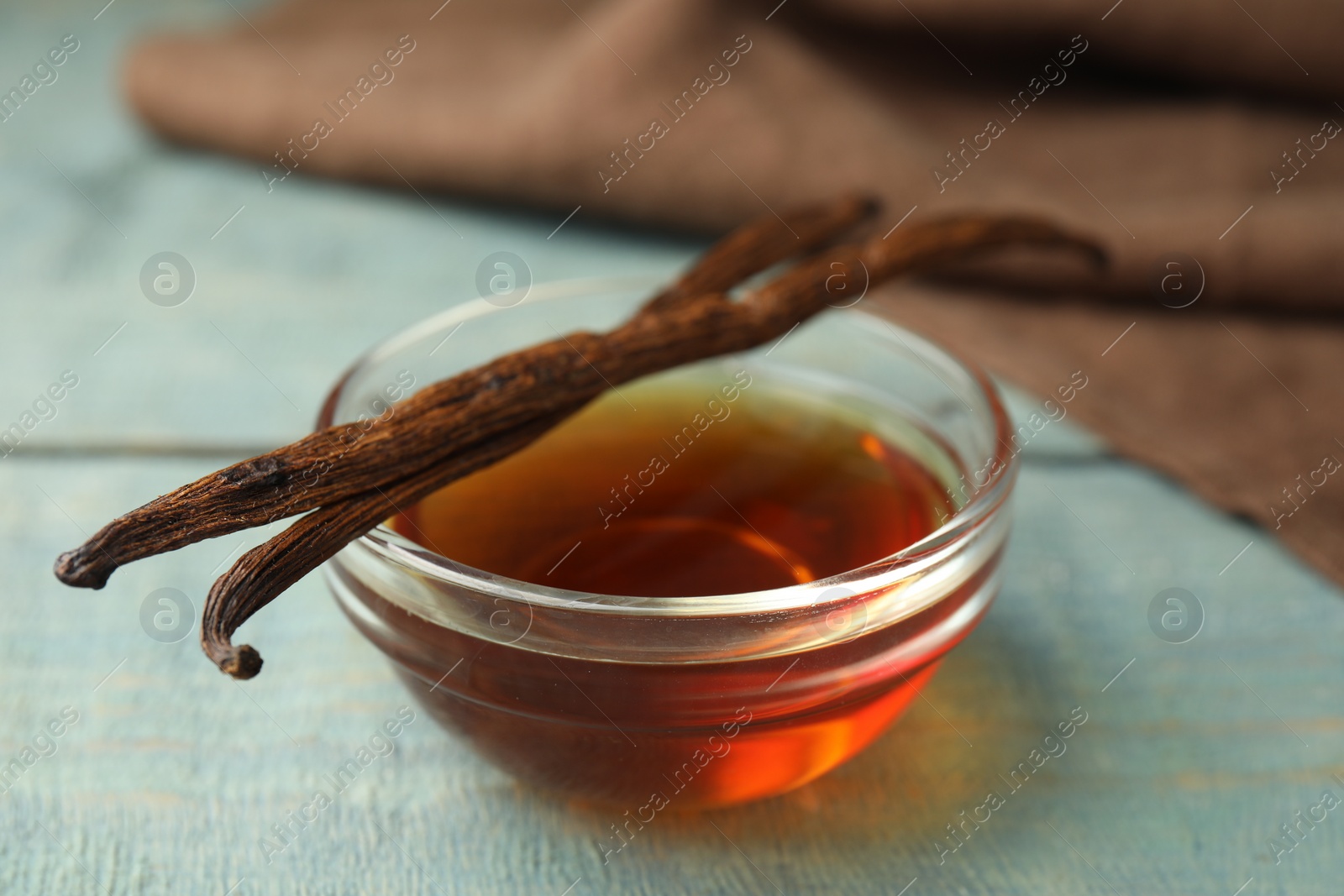 Photo of Aromatic homemade vanilla extract on light blue  wooden table, closeup