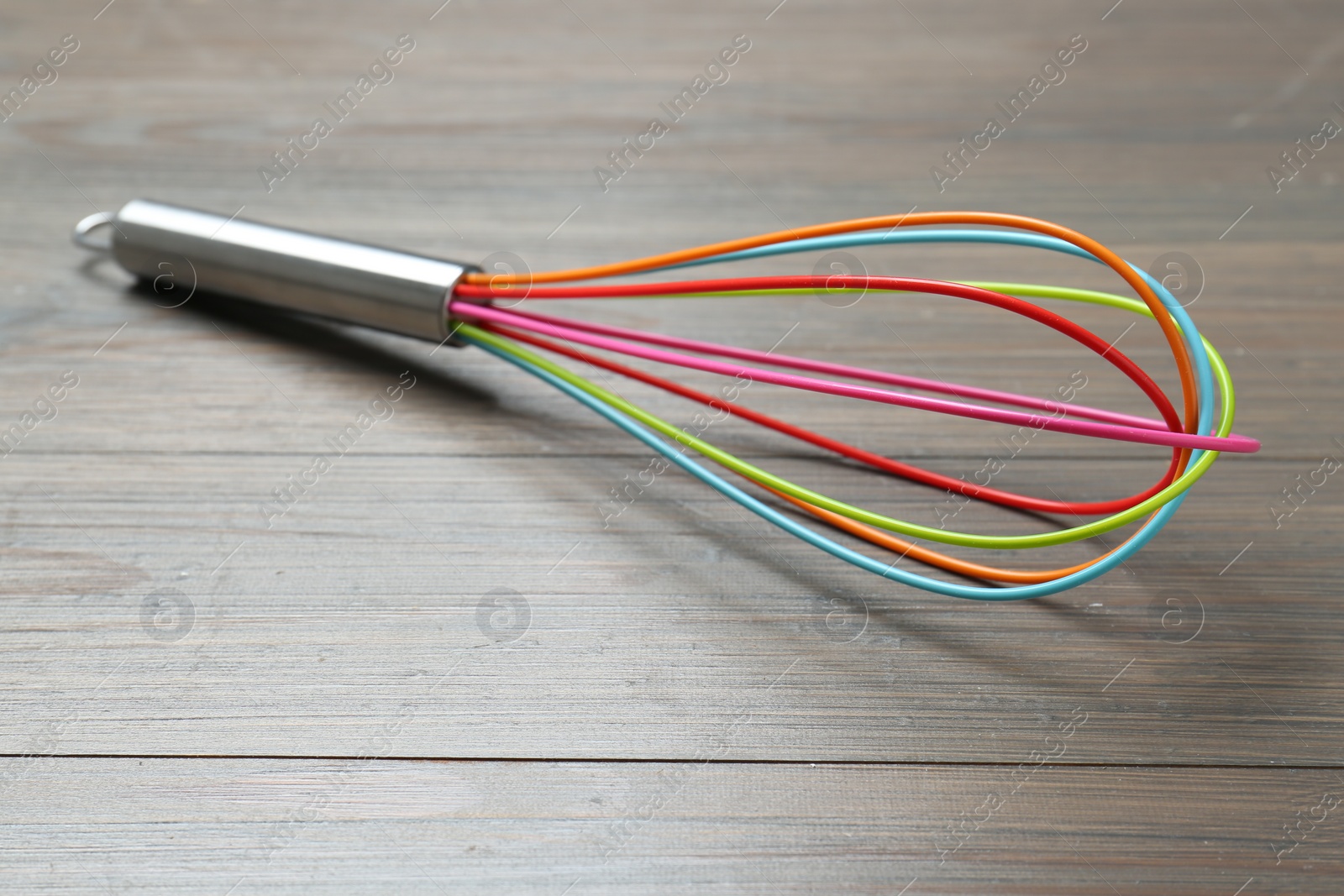 Photo of One whisk on wooden table, closeup. Kitchen tool