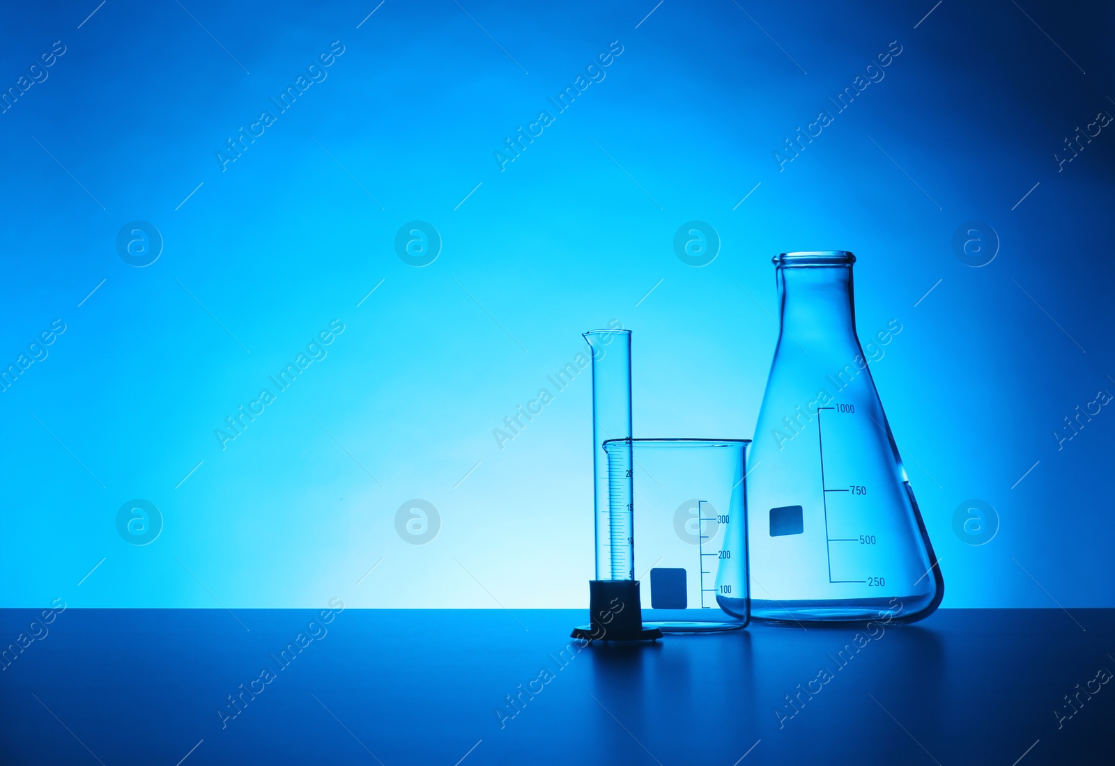 Photo of Empty chemistry laboratory glassware on table against color background