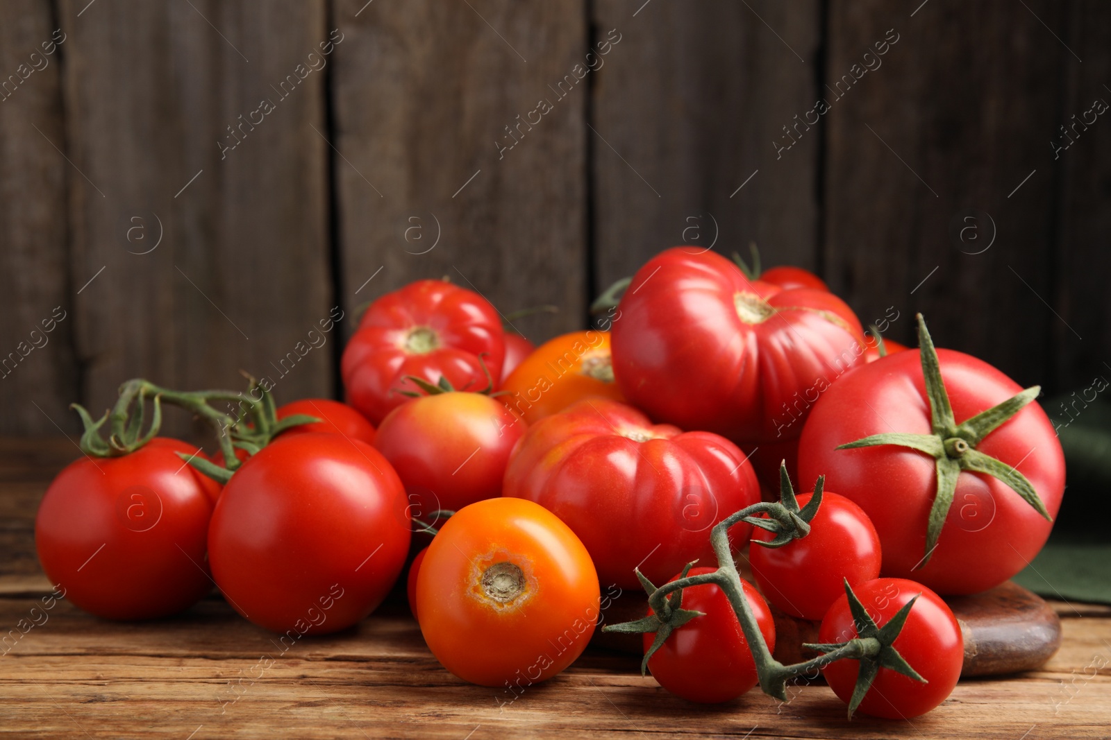 Photo of Many different ripe tomatoes on wooden table