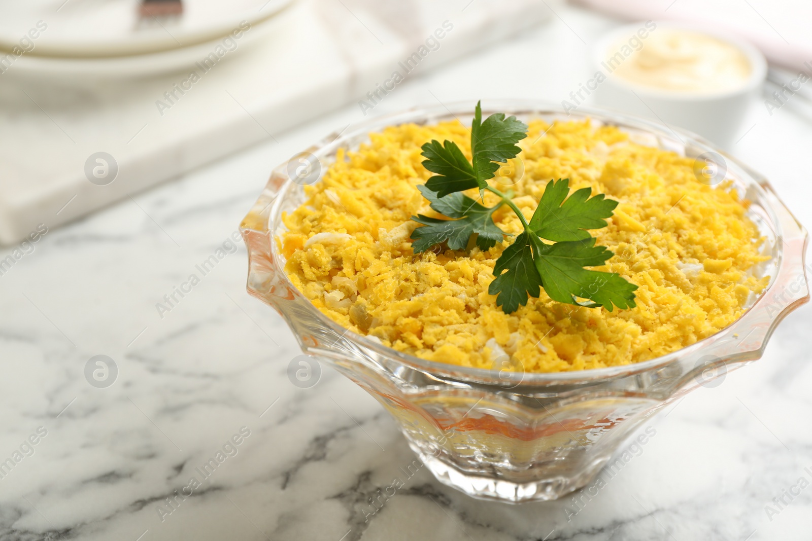 Photo of Traditional russian salad Mimosa served on white marble table