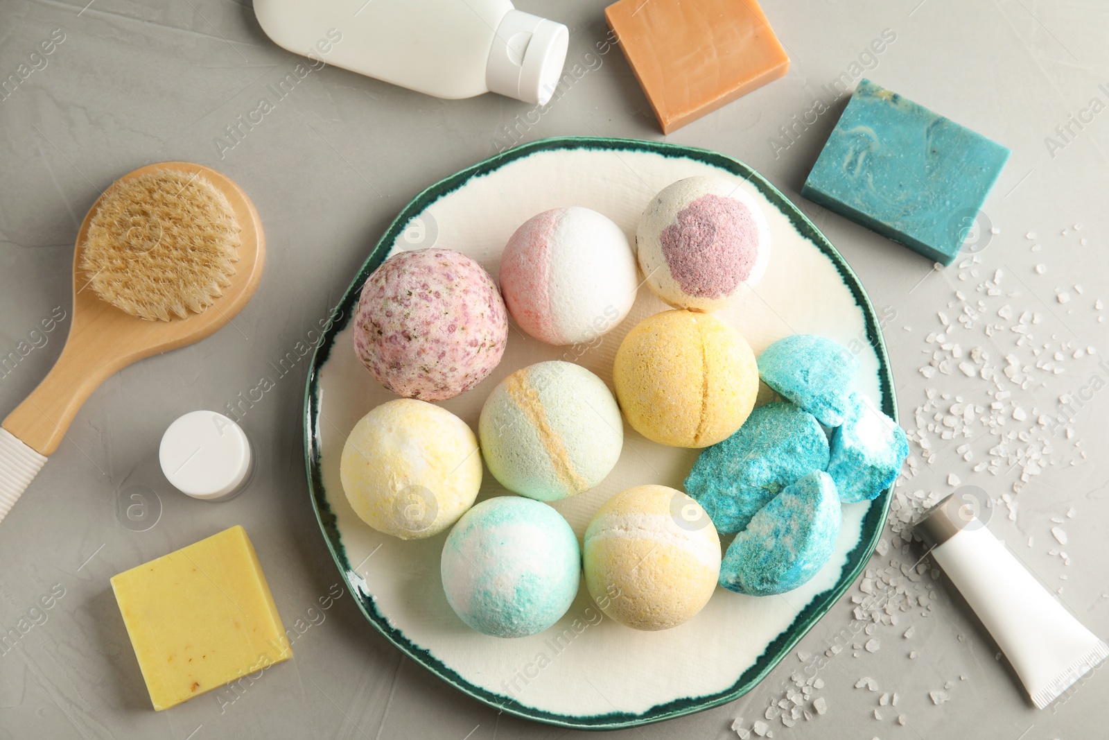 Photo of Flat lay composition with bath bombs and toiletries on grey background