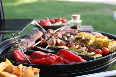 Tasty meat and vegetables on barbecue grill outdoors, closeup