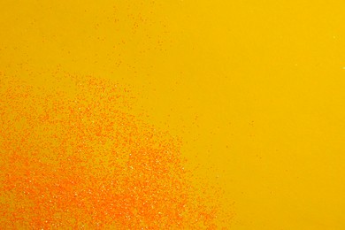 Photo of Shiny bright glitter on yellow background, flat lay. Space for text